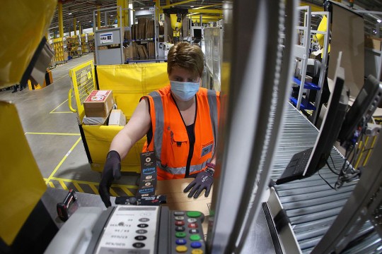 person working in Amazon packing center printing a label for a box.