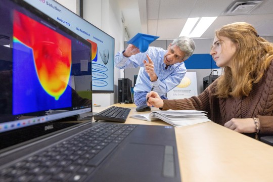 two people discusses infrared breast images in a lab.