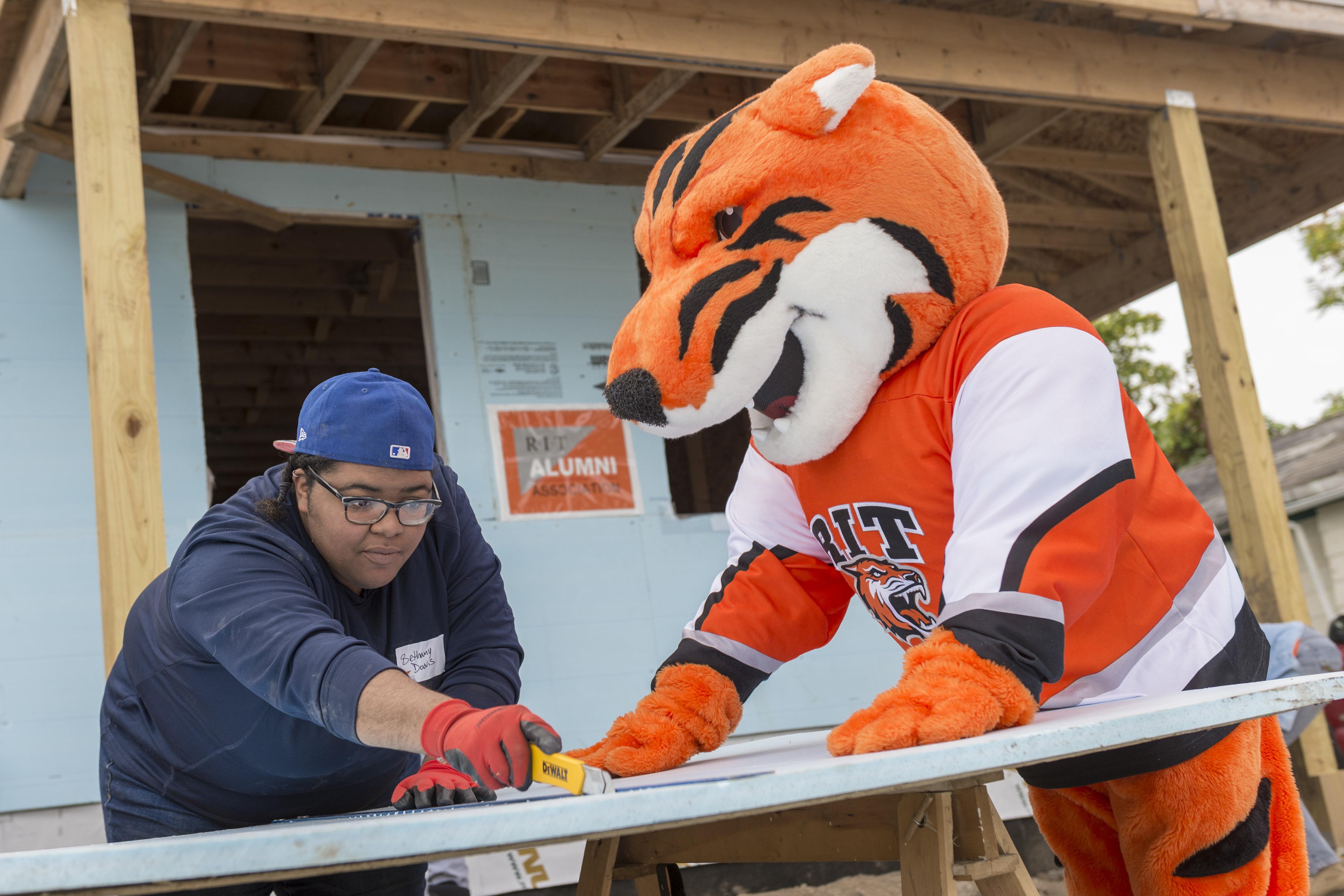 RIT mascot Ritchie working with a person