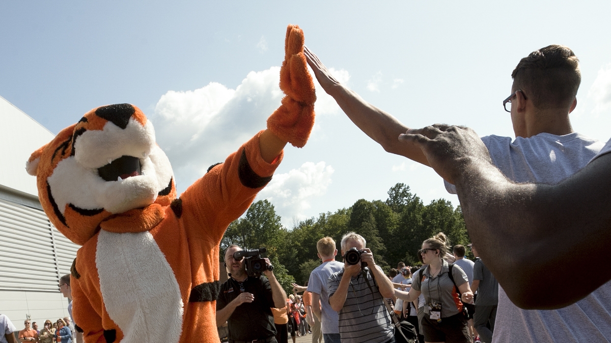 Ritchie the tiger mascot giving high fives to students.