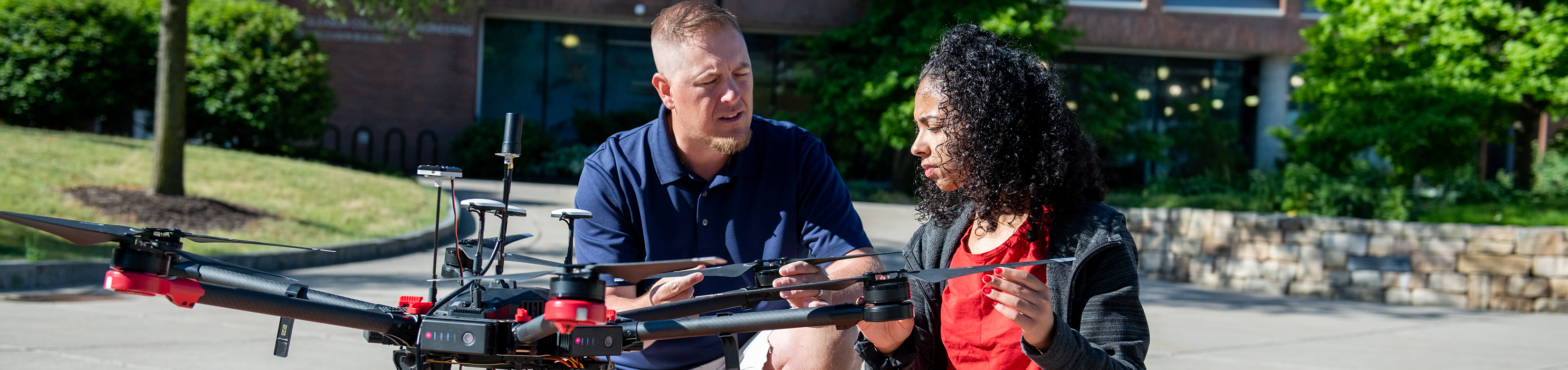 Professor and student studying drone technology, showing diverse ethnicities and gender