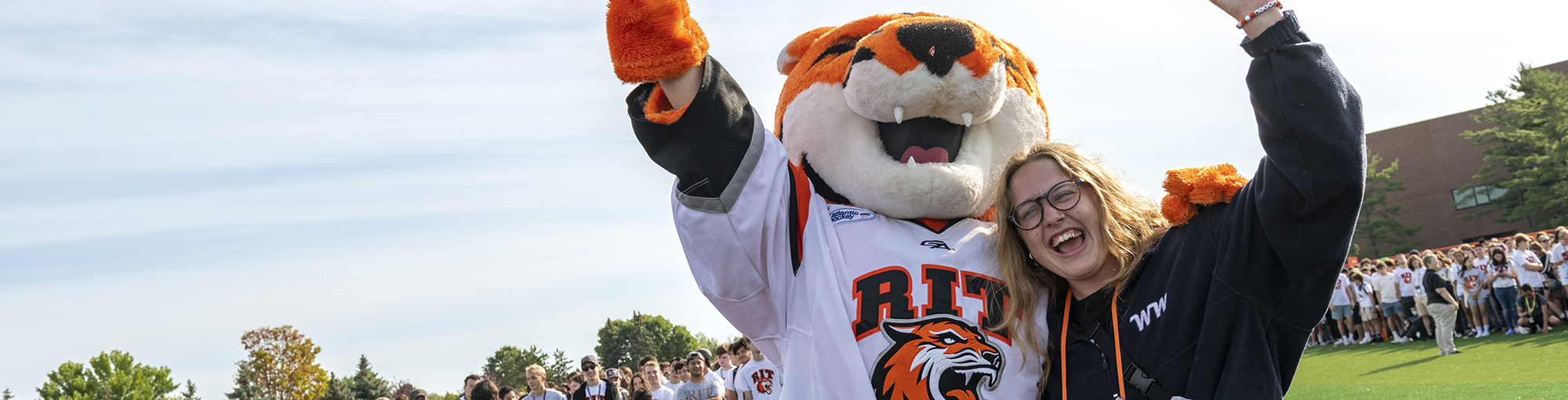 A student posing with RIT mascot RITCHIE