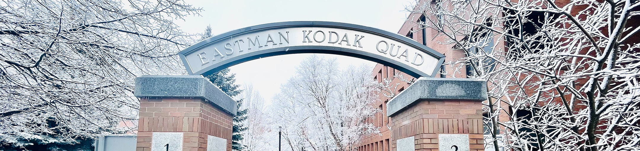 an arch that says Eastman Kodak Quad on it covered in snow