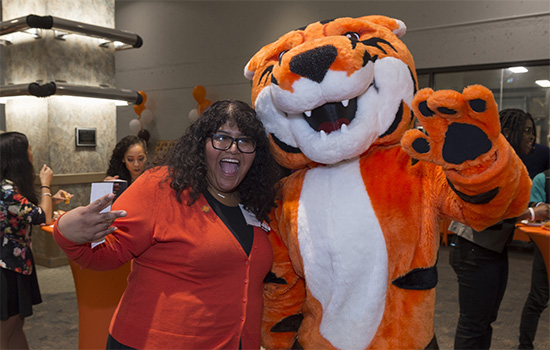 An alumni posing with RITchie, the RIT mascot.