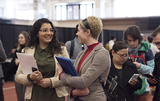 Two people talking to each other at a career fair.