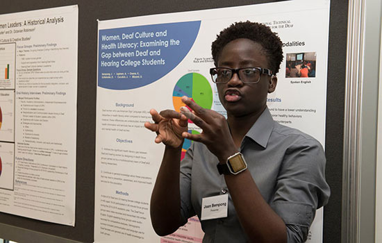 A person speaking in front of a poster.