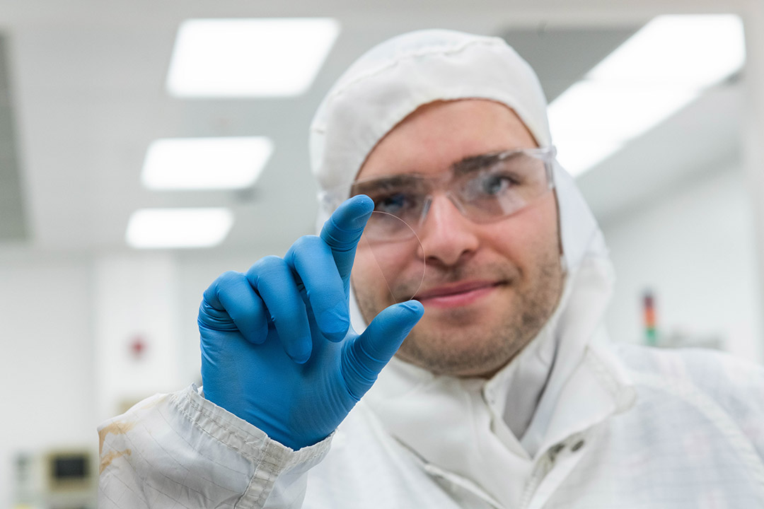 man in a lab coat holding a piece of glass