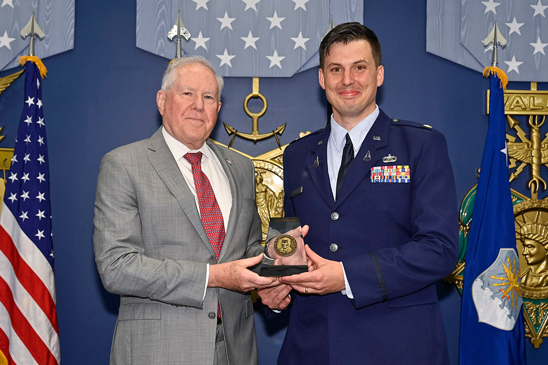 two men holding an award and posing for a photo