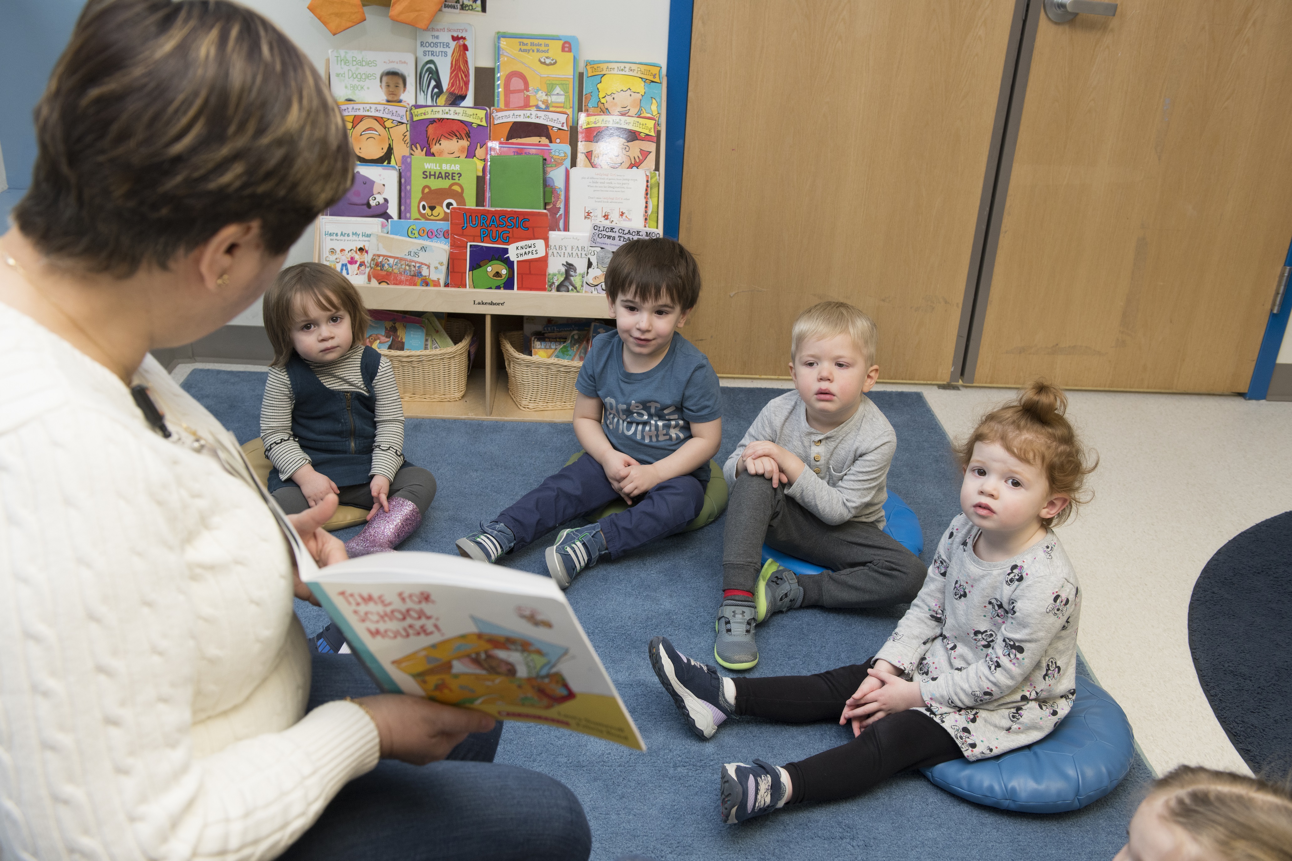 a group of children sitting and having a book read to them