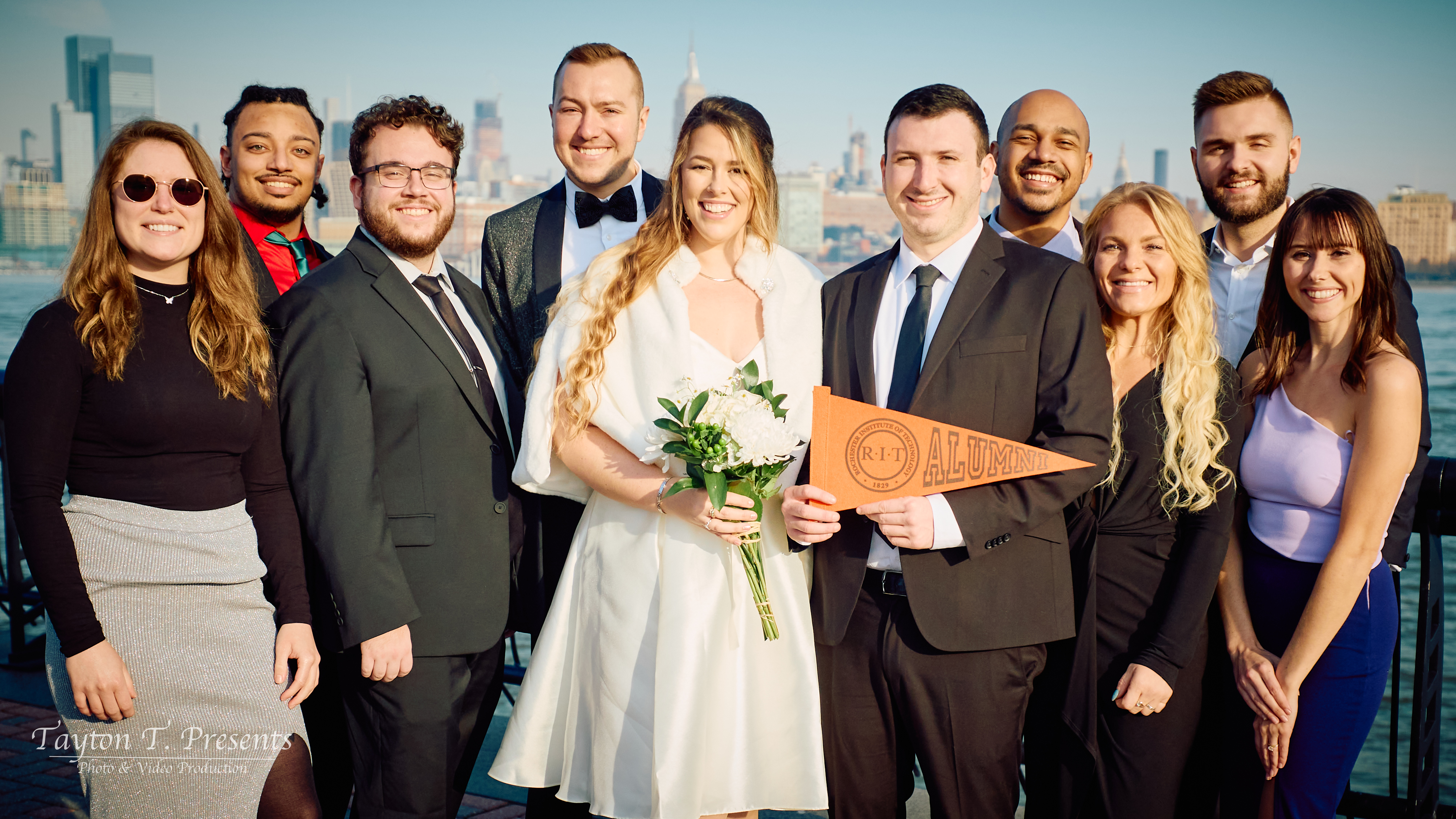a group of people posing for a wedding group photo with a skyline backdrop