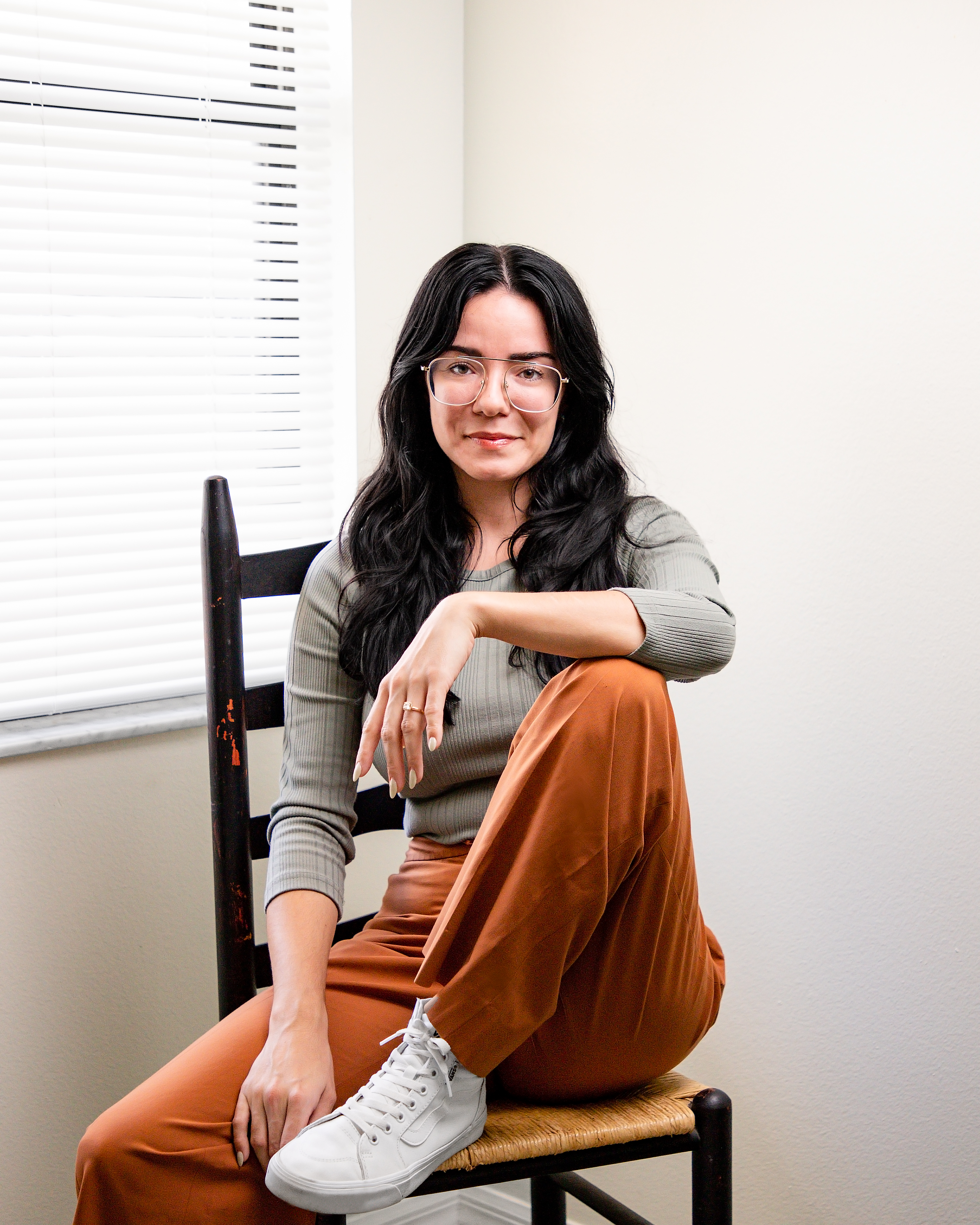 a headshot of a woman with black hair sitting on a chair