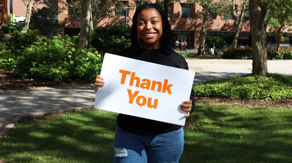 a student holding a thank you sign