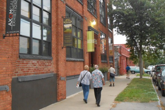 People walking past the "Axom Gallery and Exhibition" building