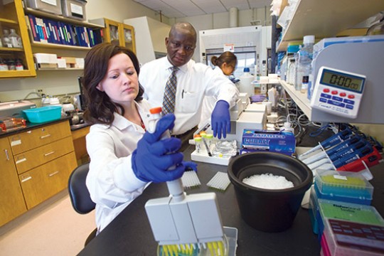 Tara Snyder works in a lab while a professor looks on and advises her.