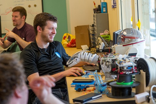 Student building robot and smiling.