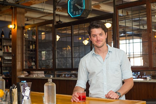 Person posing in behind table at bar