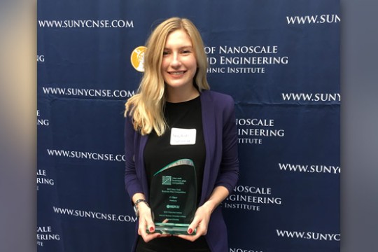 Person posing with award at conference