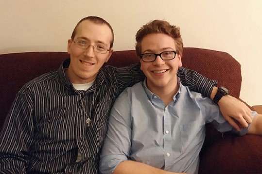Two people posing for camera on couch