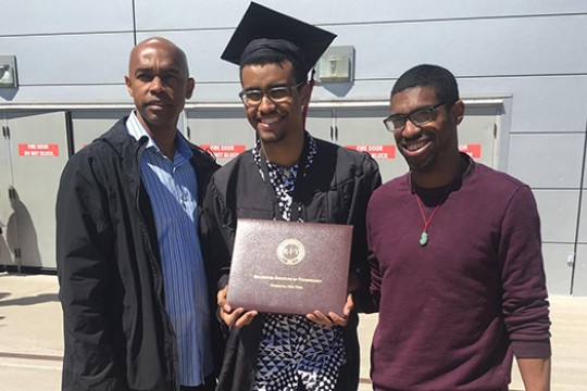 family members standing on either side of college graduate.