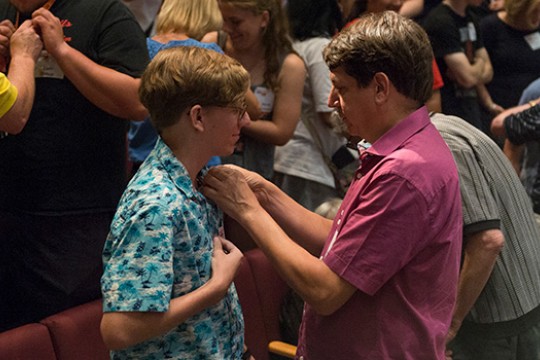 Father pinning something on son's shirt.