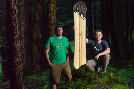 Two people posing with board in forest