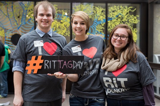 Three students in matching shirts that say "I heart RIT donors" pose for a picture.