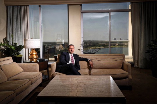Man in suit sits on sofa in room.