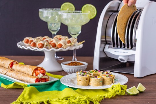 Table with tortilla toaster and platters of tortilla-based appetizers.