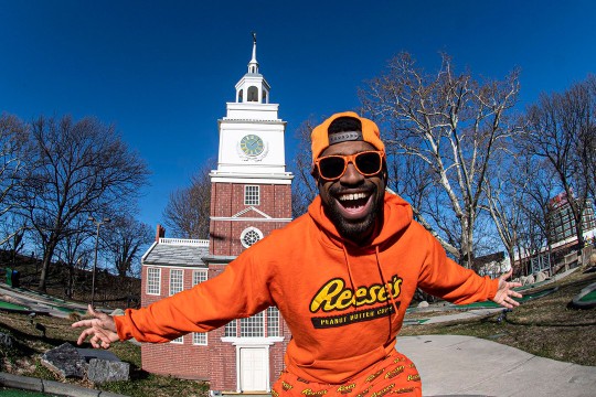 smiling man wearing orange Reese's hat, sweatshirt and pants.