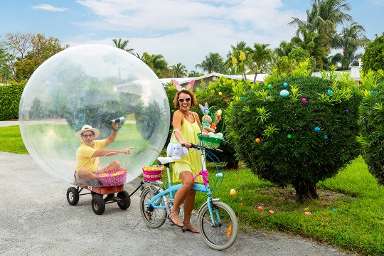 George Kamper in a bubble on a wagon being pulled by his wife on a bike.
