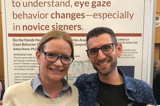 two researchers posing in front of poster presentation.