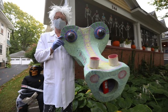 man dressed like mad scientist standing with papier mache dragon head.