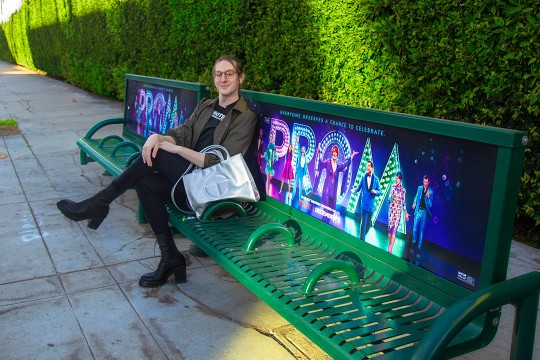 person sitting on a bench promoting the movie 'The Prom.'