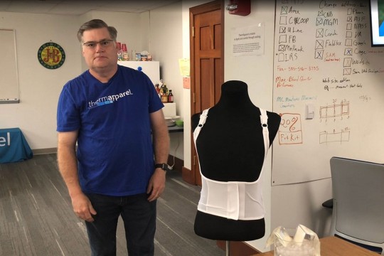 man standing next to a mannequin wearing a cooling vest.