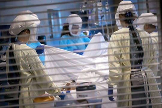 COVID-19 patient receiving care from nurses wearing protective gear.