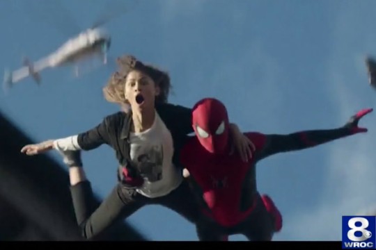 still from a movie with Spider-Man jumping while holding a woman.