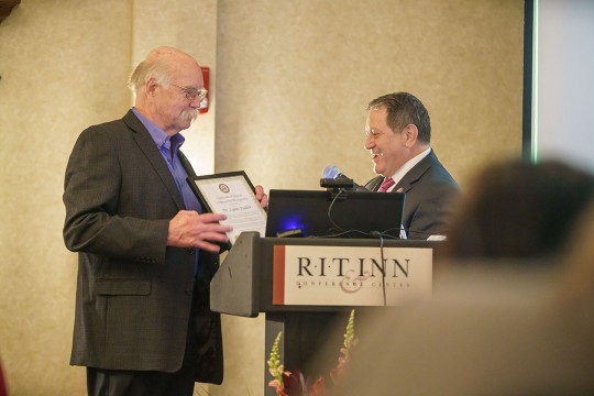 professor receiving an award at a podium.