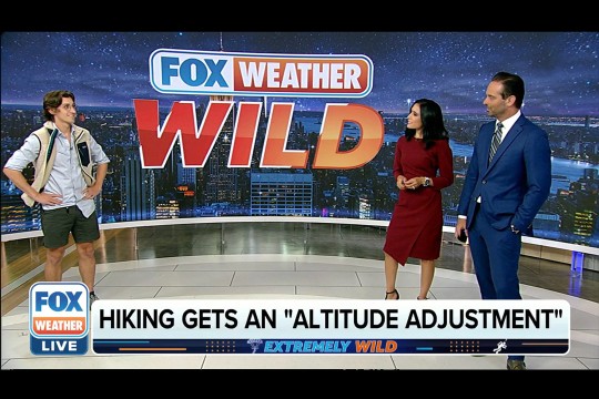screenshot of a TV studio where a hiker is talking to two news anchors with the words Fox Weather Wild, hiking get an altitude adjustment.