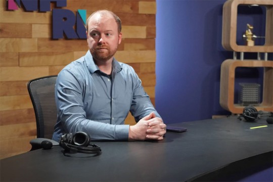man sitting at a table with his hands folded.