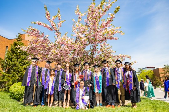 Saunders graduates standing in front of tree