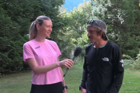 person with a microphone interviewing a runner outdoors.