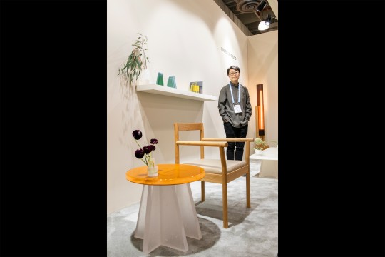 Alumna Bowen Liu poses next to furniture pieces she created.