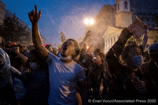 A group of people protest as heavy rain falls.