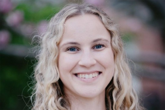 Amanda Goodhines is shown in a headshot with curly blonde hair and blue eyes