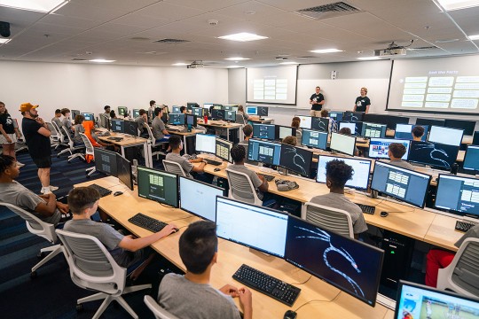 students in Camp Tiger sit in a classroom learning about cybersecurity.