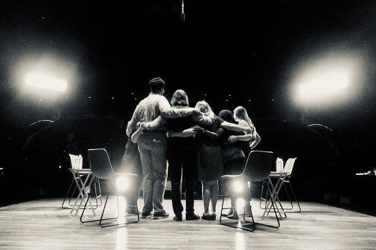 a black and white photo of the cast shown facing the audience.