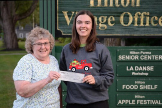 Linda Viney (left) presented Daniela Lincoln with a $100 award and a sweatshirt embroidered with her winning logo on behalf of the Hilton Apple Fest board of directors. 