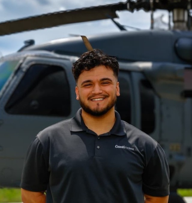 A photo of  Jesse Bairan ’21 (CET) in front of the display helicopter at Aviano Air Base, Italy.