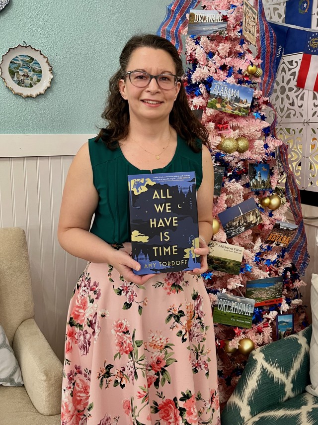 Amy Tordoff holds her debut novel, All We Have is Time, at a themed tea party in Colorado Springs.