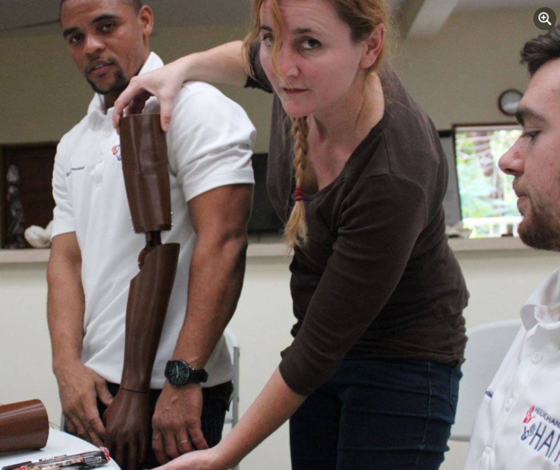 Jade holding a prosthetic arm while two others look on